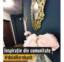 Dekorativ rund väggspegel med guldram i bladform bredvid rosa pioner i en glasvas i en modernt inredd hall.