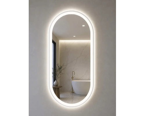 Oval badrumsspegel med LED-belysning runt om, som speglar ett modernt ljust badrum med fristående badkar.