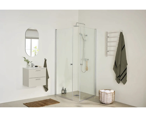 Modernt badrum med hörn-duschkabin, vägghängt tvättställ, oval spegel och handdukshängare i minimalistisk design.