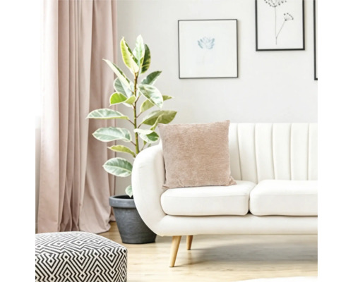 Vardagsrum med modern soffa, beige kudde, krukväxt och geometrisk sittpuff i en ljus och ombonad inredning.