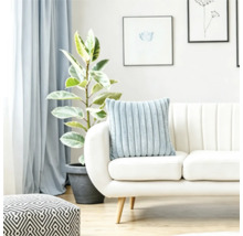 En mjuk räfflad kudde på en ljus soffa i ett ljust vardagsrum med en växt och en geometrisk sittpuff.