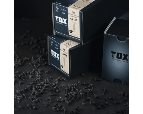 Tox profilskruv Dry i två olika storlekar på bordet, med ett stort antal lösa skruvar utspridda.