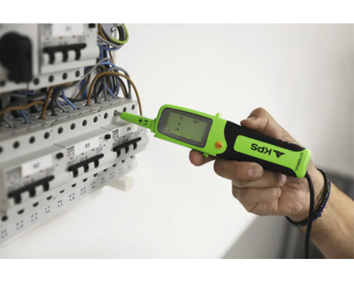 En hand använder en digital spänningsprovare av märket KPS på en undercentral med automatsäkringar för elektrisk mätning.