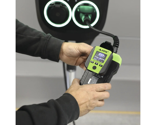 Laddstationstestare KPS FASTCHECK 3010 med digital display för kontroll av laddstolpar för elbilar hållen i en hand.