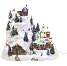 Julvinterlandskap med hus, skidåkare och julgranar på en snöklädd kulle