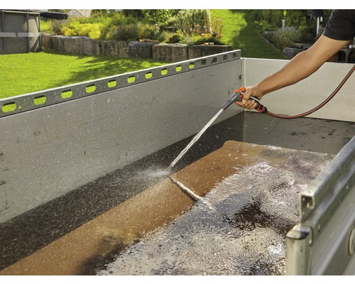 En person rengör en släpvagn med en trädgårdsslang.