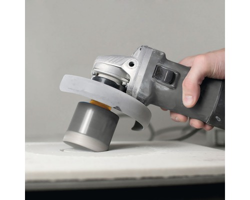 En hand använder en vinkelslip med tillbehör för att slipa en yta