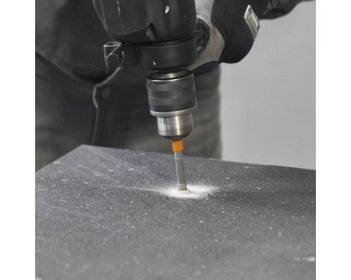 Hantverkare borrar ett hål i en yta med en borrmaskin.