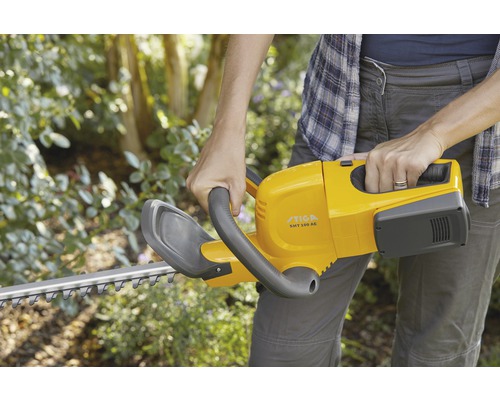 En person håller en gul Stiga häcksax.