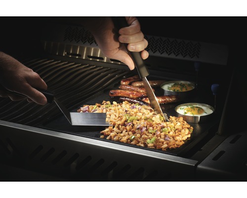 Tillagning av potatiskakor, korv och stekt ägg på en grillplatta med verktyg.