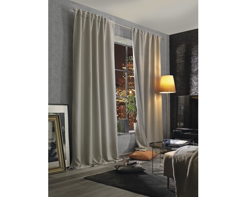 Vardagsrum med gardiner, golvlampa och utsikt över staden på natten