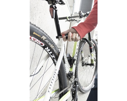 Närbild av en cykel vars sadelstolpe justeras med ett verktyg.
