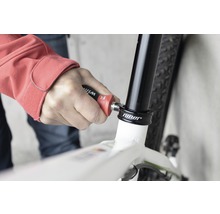 En person använder verktyg på en cykel för reparation.