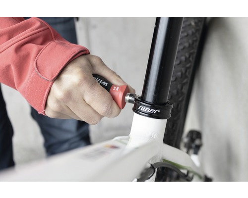 En person använder verktyg på en cykel för reparation.
