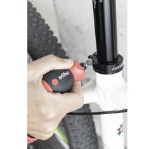 En person fäster en cykelsadelstolpe med en Wiha-skruvmejsel.