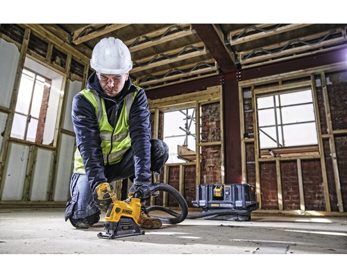 En byggnadsarbetare i skyddskläder använder en DeWalt väggfräs på en byggarbetsplats.