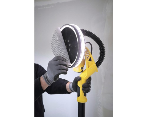 En person fäster sandpapper på en gipsslipmaskin med LED-belysning.
