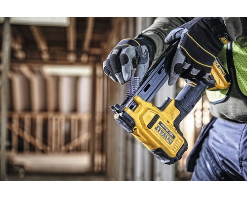 En person lägger spik i en gul Dewalt batteridriven spikpistol.