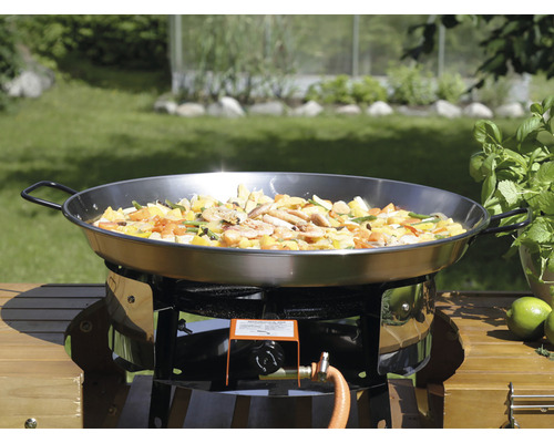 Paellapanna på gasspis med grönsaker och skaldjur i trädgården