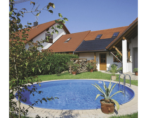 Rund pool i trädgården med bostadshus i bakgrunden.