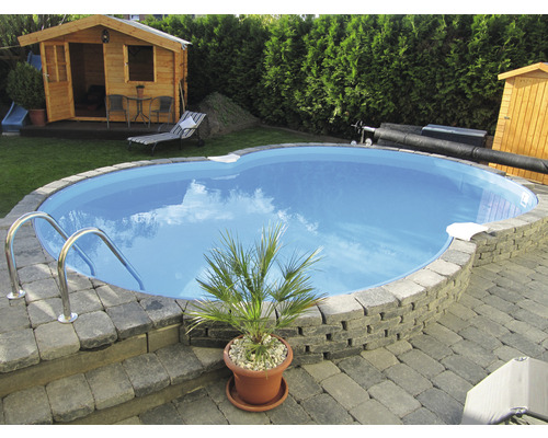 Trädgård med pool, stenmur, trähus och trädgårdsmöbler.