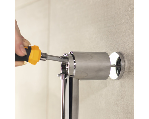 Installation av ett förkromat stödhandtag med en skruvmejsel i badrummet.