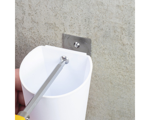 Montering av en vit tandborstmugg med en skruvmejsel på en vägg