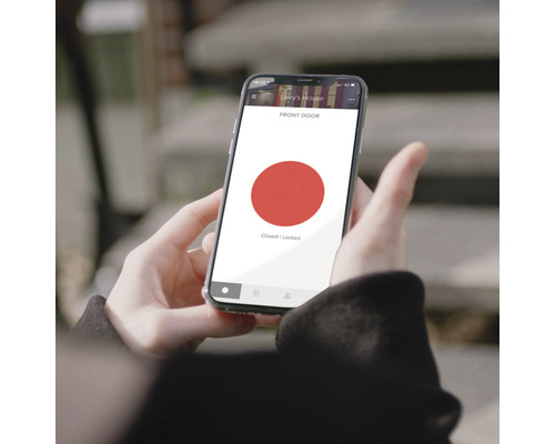En person håller en smartphone som visar en app för att styra ett dörrlås som är stängt och låst.