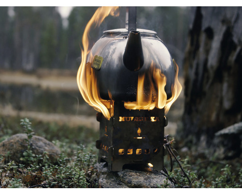Tekanna på ett spritkök med lågor i en naturlig miljö.