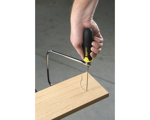 En figursåg skär en träbit. Användaren håller i sågens handtag.