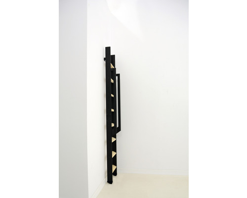 Svart trästeghylla mot en vit vägg