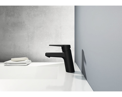 Svart tvättställsblandare på ett vitt handfat med handdukar och tvål