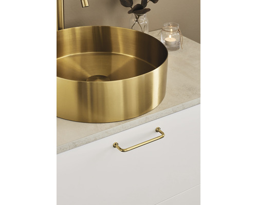 Guldfärgad tvättställsskål på ett badrumsskåp med handtag