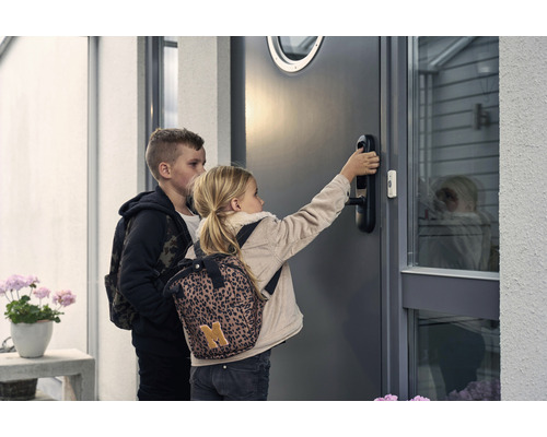Två barn framför en ytterdörr med ett digitalt dörrlås