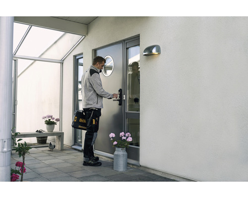 Hantverkare öppnar ytterdörren med verktygsväska framför husets entré.