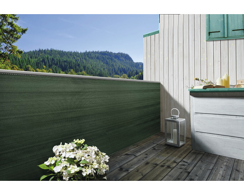 Scen av en terrass med insynsskydd, trägolv och byrå