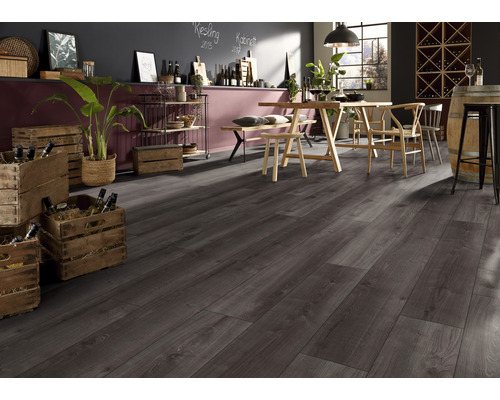 Interiör av ett rum med mörkgrått laminatgolv, träbord med stolar, hyllor och vinlådor