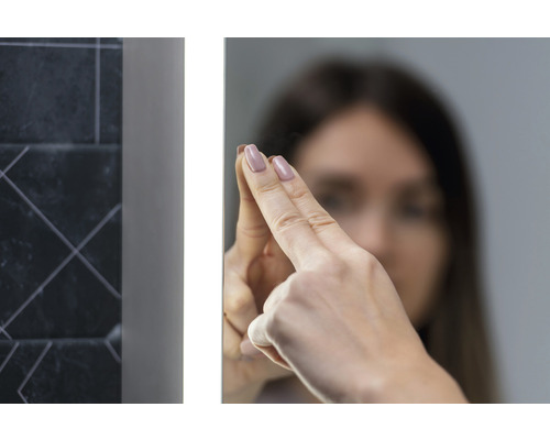 Kvinna rör en belyst badrumsspegel