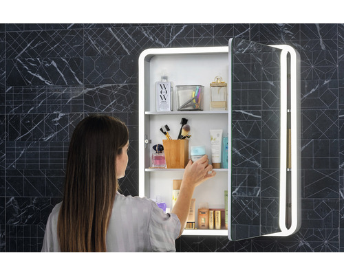 Kvinna framför ett spegelskåp med belysning i badrummet