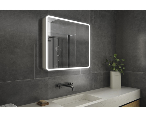 Badrum med belyst spegelskåp, tvättställ och kran.