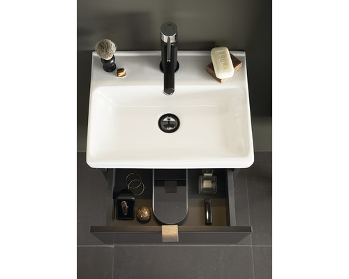 Badrumshandfat med blandare, tvål, rakborste och öppen låda med badrumsartiklar