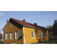 Gult hus med rött tak och flera fönster.