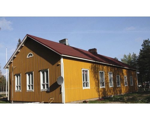 Gult hus med rött tak och flera fönster.