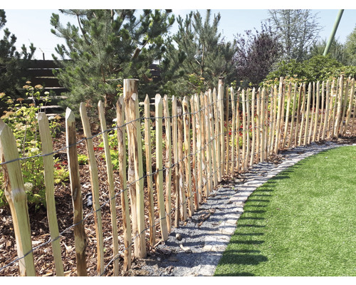 Trästaket avgränsar en trädgårdsdel med gräsmatta.