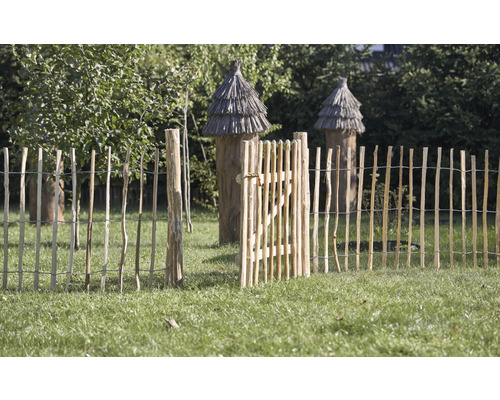 Trädgårdsscen med öppet trästaket och bikupor i bakgrunden