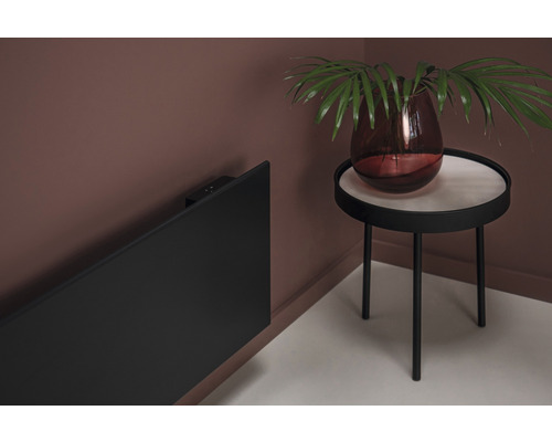 Scen med en svart radiator på väggen och ett sidobord med en vas