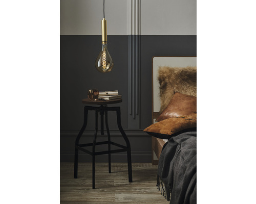 Sovrumsscen med hängande lampa över en pall, böcker och ett glas