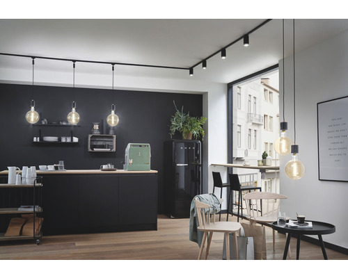 Modernt kök med svart köksdel, matbord och skensbelysning