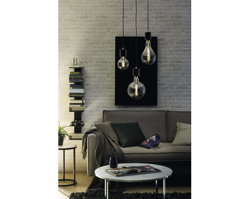 Vardagsrum med soffa, soffbord och en taklampa med tre lampor