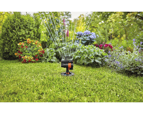 Grässpridare i trädgården som vattnar